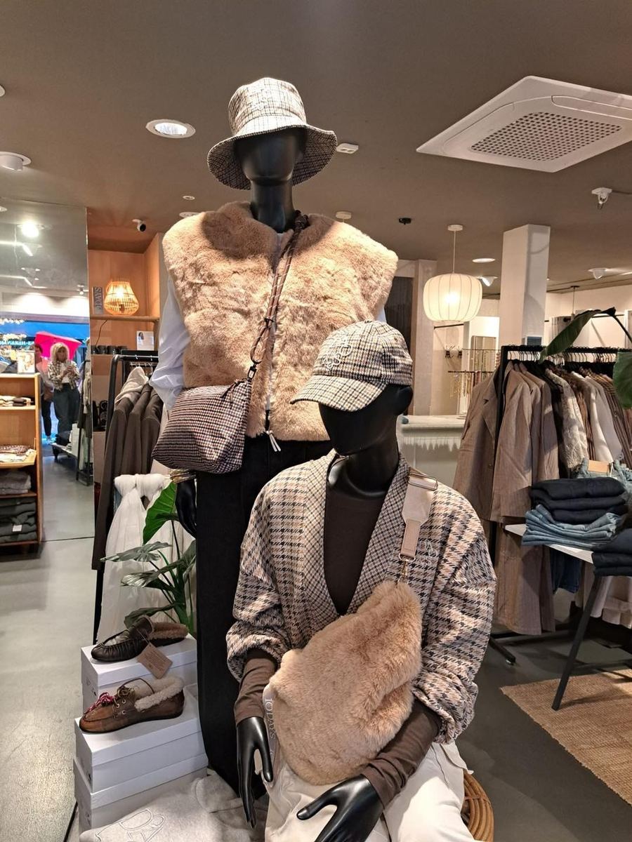 Twee etalagepoppen in de winkel met een teddy gilet, ruitjes en een bucket hat