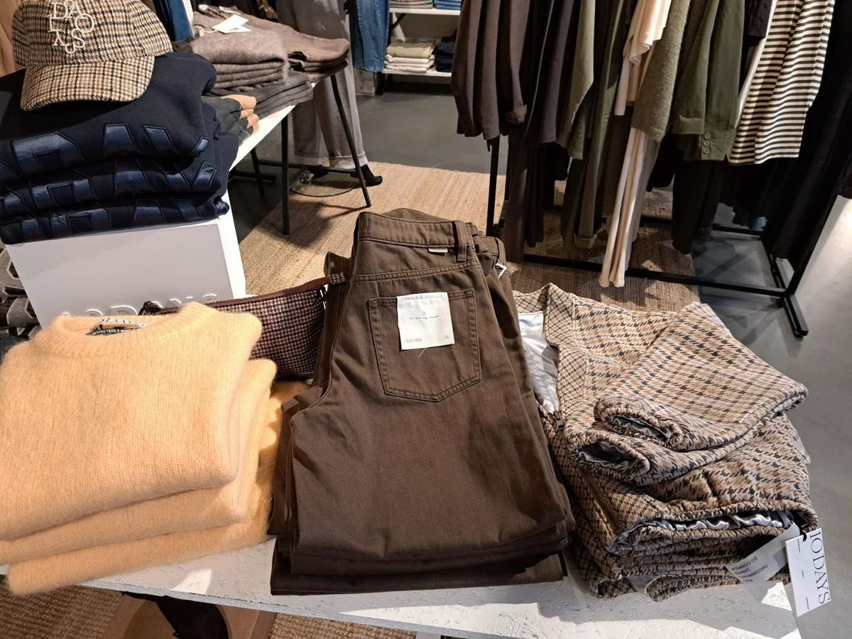 Tafel in de winkel met gebreide truien, bruine broeken en ruitjesstof