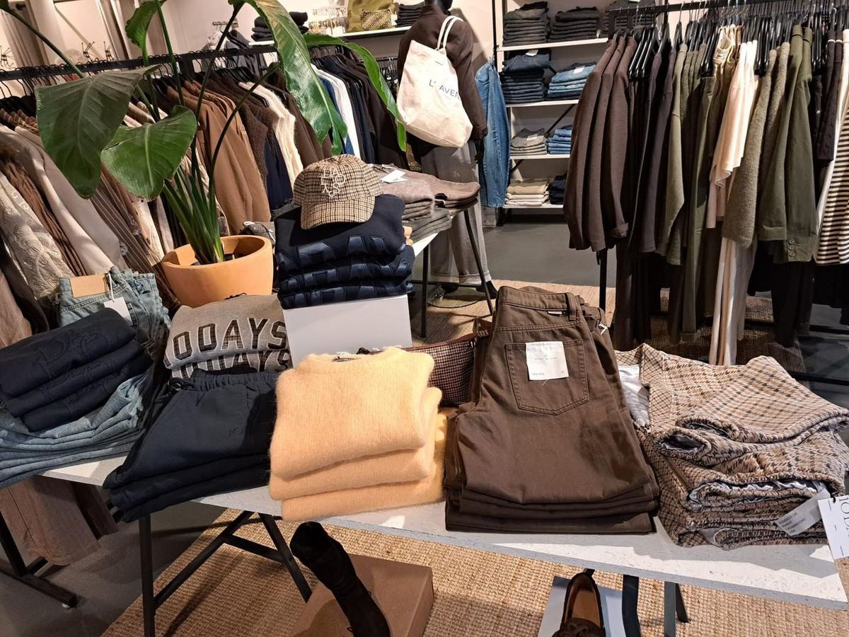 Tafel met truien, broeken en ruitjes tussen de rekken in de winkel